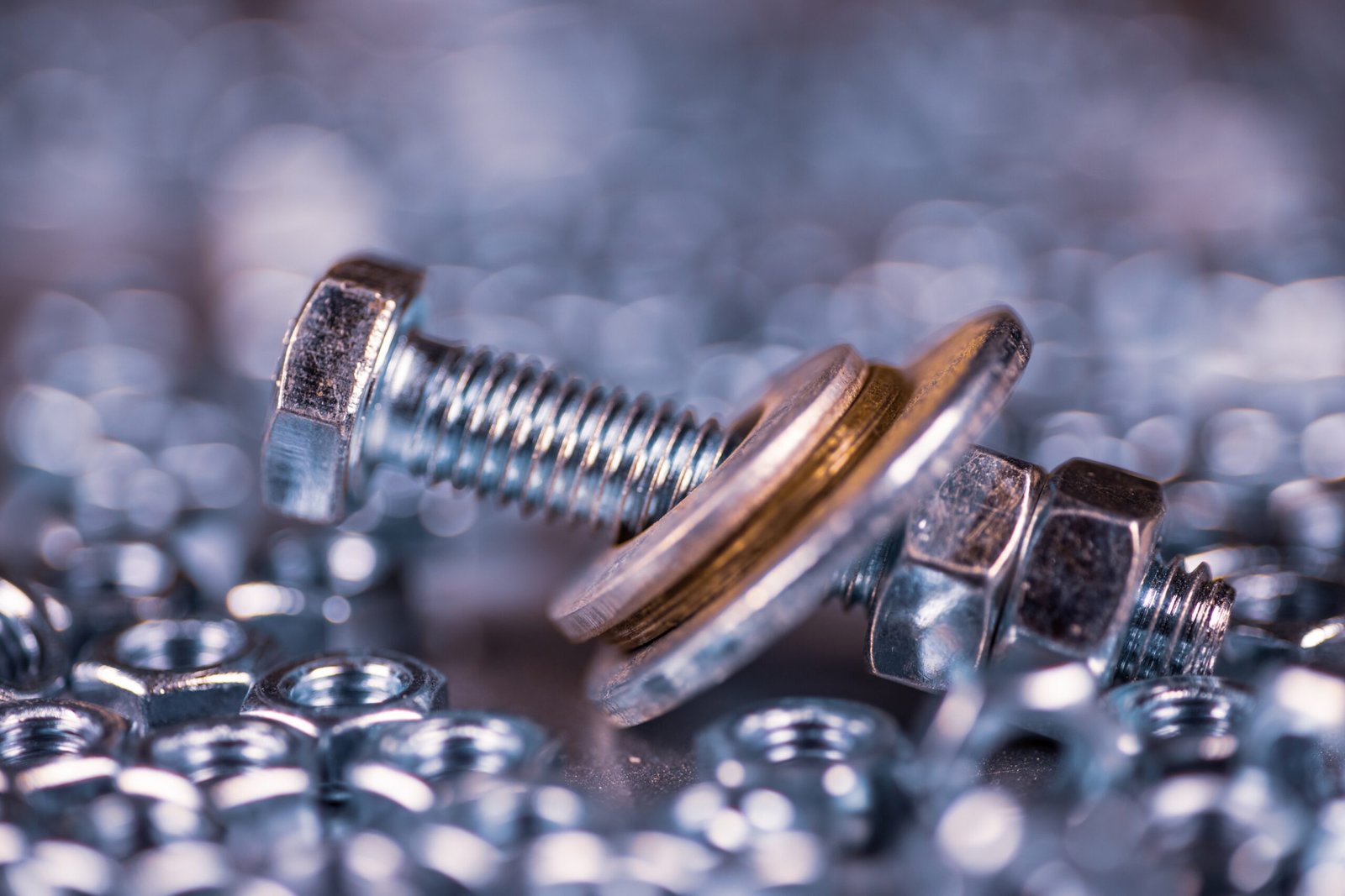 Close-up metal chrome bolts and nuts in a chaotic order. Background concept for fasteners and construction topics. Repair and spare parts concept